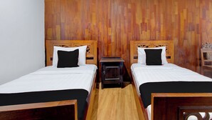 Une chambre avec deux lits, des têtes de lit en bois, une petite table de chevet en bois et un panneau mural en bois.