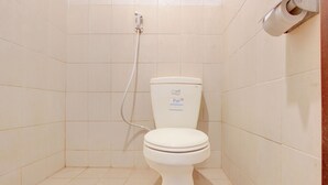 Une petite salle de bain propre, équipée de toilettes, d’une douche et d’un porte-rouleau de papier toilette.