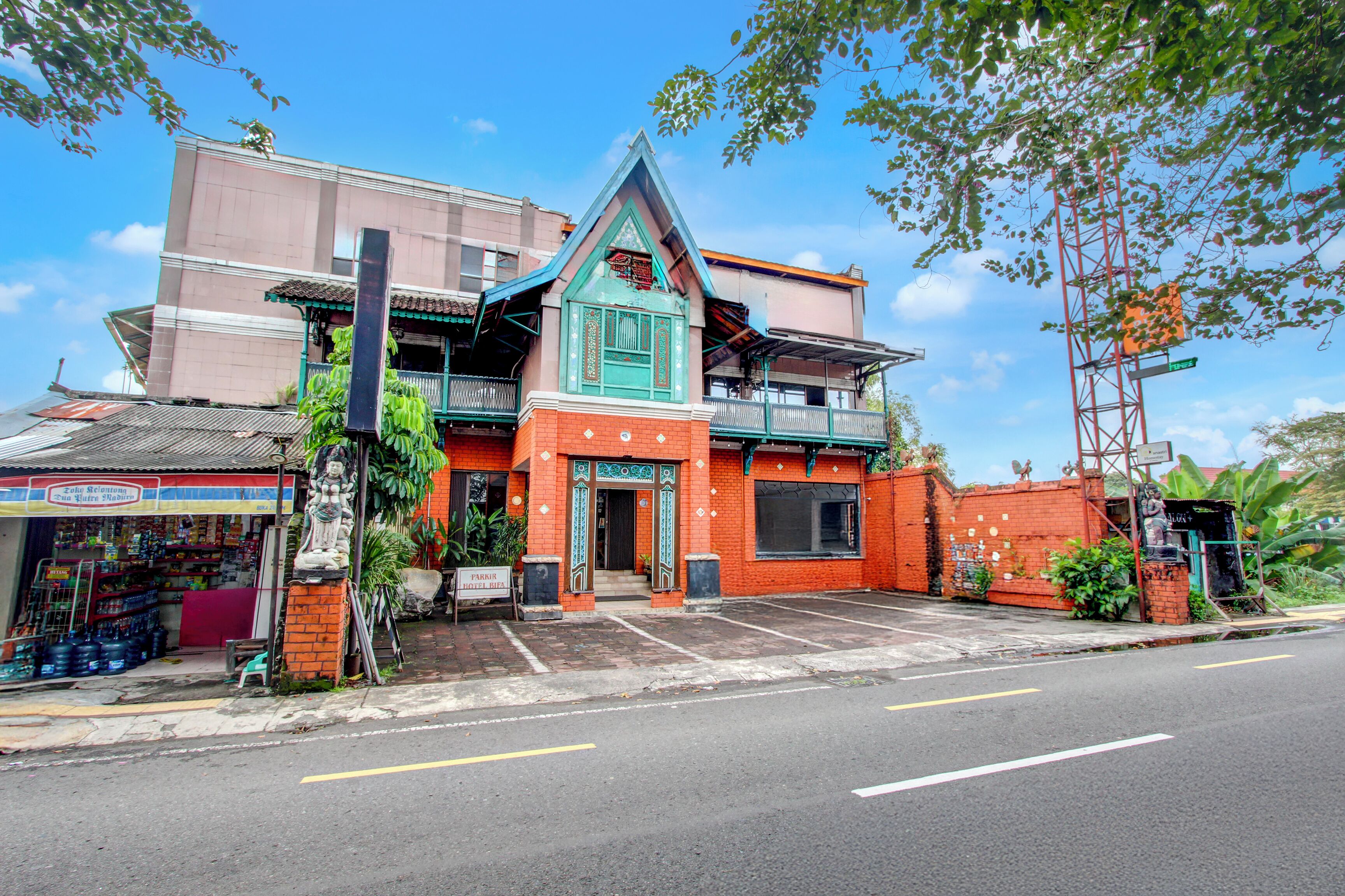 A two-story building with a red facade, a green roof, and a small balcony.