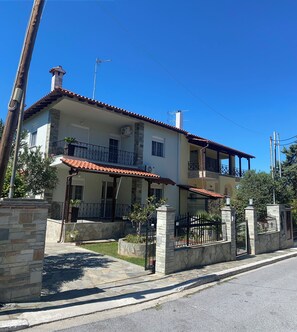 A two-story house with a tiled roof, stone walls, and a gated entrance. - Villa with pool (Perea)