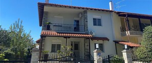 A two-story building with a tiled roof, a balcony with a metal railing, and a stone wall. - Villa with pool (Perea)