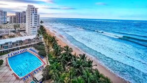Un hotel sul lungomare con piscina, spiaggia e vista sull'oceano.