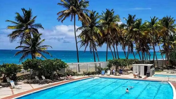 Una piscina con palme e vista sull'oceano.