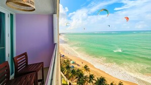 Un balcone con vista sulla spiaggia, una lampada di vimini a soffitto e un tavolo di legno.