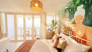 Una camera da letto con un letto, un'ampia finestra, un balcone e un quadro.
