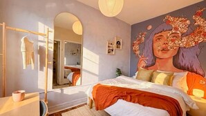Una camera da letto con un letto, uno specchio, un armadio e un affresco al muro.