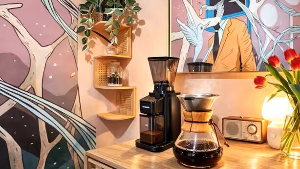 Una macchina da caffè, una radio e una pianta su un tavolo di legno.