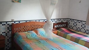 Un dormitorio con cama, mesita de noche, aire acondicionado instalado en la pared y pared con azulejos.