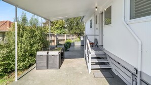 Een overdekt terras met zitplaatsen en uitzicht op het omliggende groen.