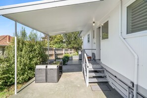 Ein überdachter Außenbereich mit Terrasse, Sitzgelegenheiten und Blick auf die grüne Umgebung.