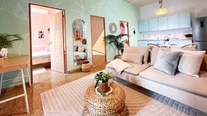 A living room with a sofa, a coffee table, a mirror, and a kitchen area in the background. - Walk to Beach!「4 Bedroom」Vacation Home w Balcony! (Canals,)
