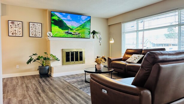 A living room with a fireplace, a television, leather sofas, and a large window. - Mainfloor 3 bedroom, sleep 5-6, Kelowna wineries retreats (Kelowna)