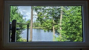 A window with a view of a lake surrounded by trees. - Baylight Cabin | Gorgeous Cabin on Private Lake (Dysart)