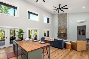 A spacious kitchen with a wooden island, a blue sofa, and a stone accent wall. - Fantastic 4-bedroom house with AC in charming Old Fort (Old Fort)