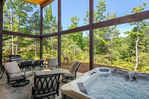 A covered outdoor area with a hot tub, seating, and a grill. - Fantastic 4-bedroom house with AC in charming Old Fort (Old Fort)