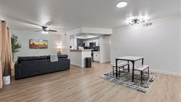 A modern living room with a sofa, a dining table, and a kitchen in the background. - Great for Mid/Long Stays - Pool - King Bed (Mesa)