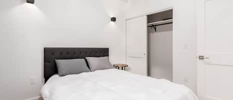 A bedroom with a bed, a bedside table, a wardrobe, and a closet.