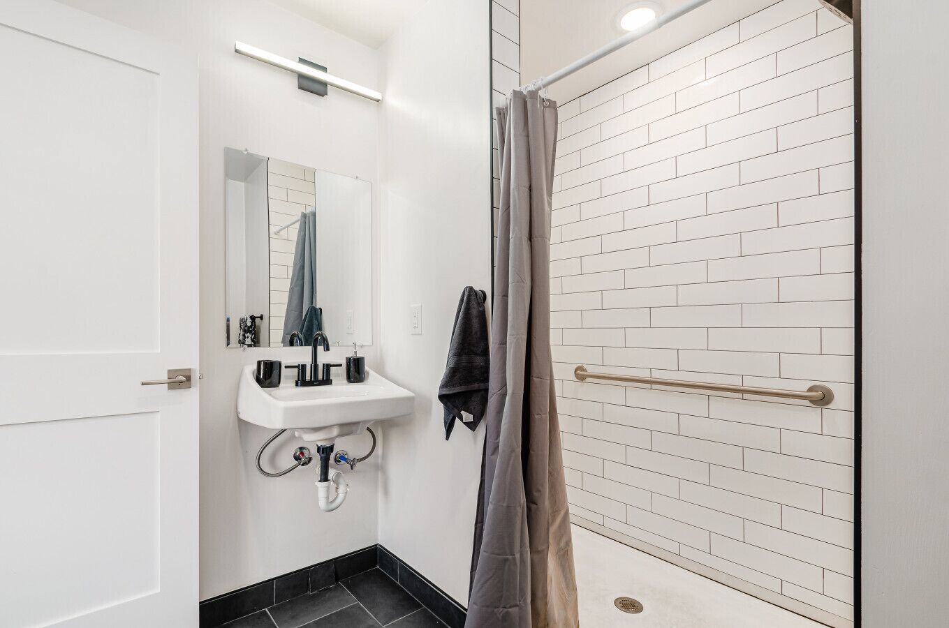 Une salle de bain avec un lavabo blanc, un miroir et une douche avec un rideau.