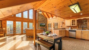 Un'ampia baita in legno con zona pranzo, cucina e ampie finestre.