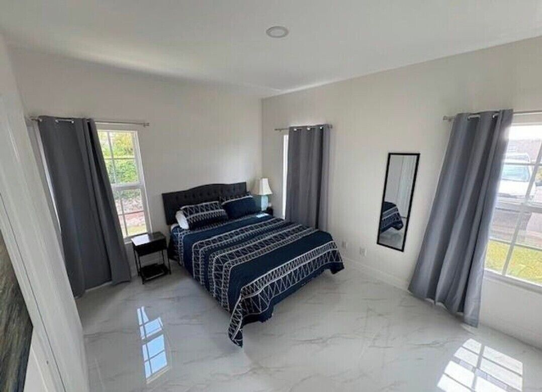 A bedroom with a bed, nightstands, a window, and curtains.