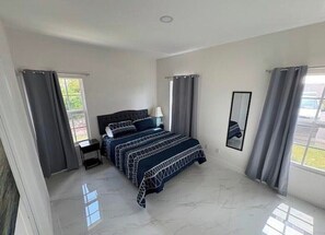 Une chambre à coucher avec un lit, des tables de chevet, une fenêtre et des rideaux.