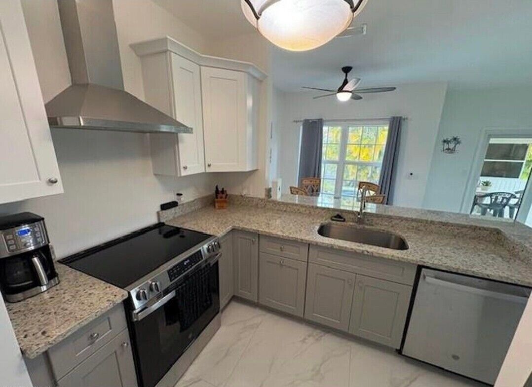 Une cuisine équipée d’une cuisinière, d’un four, d’un lave-vaisselle et d’une fenêtre donnant sur un beau paysage.