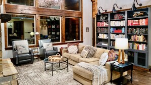 Un salon chaleureux avec une grande fenêtre, une bibliothèque et une cheminée.