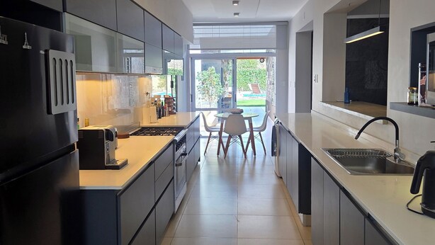 Cozinha moderna com ilha central, eletrodomésticos embutidos e vista para o exterior.