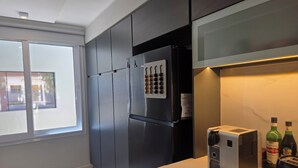 Uma cozinha moderna com frigorífico embutido, máquina de café e janela com vista para o exterior.