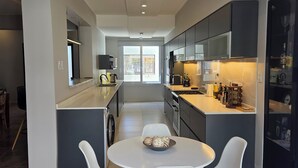 Uma cozinha moderna com uma ilha central, cadeiras brancas e uma mesa de jantar.