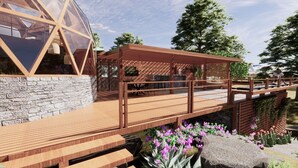A wooden deck with a pergola, stone wall, and outdoor seating area.
