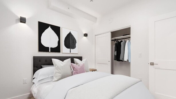 Una camera da letto moderna con un letto grande, un armadio e due lampade fissate al muro.
