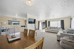 Amplia sala de estar con una mesa de comedor, sofás y una cocina con televisor.