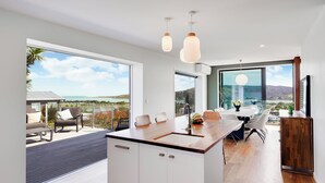 A modern kitchen with a large island, a dining area with a view, and a patio with outdoor seating.