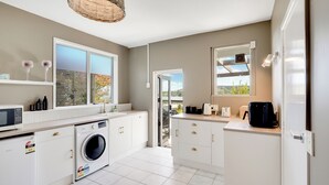 A modern kitchen with a washing machine, a microwave, and a large window.