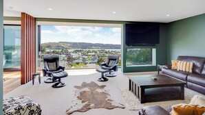A modern living room with a large window, leather furniture, and a view of a landscape.