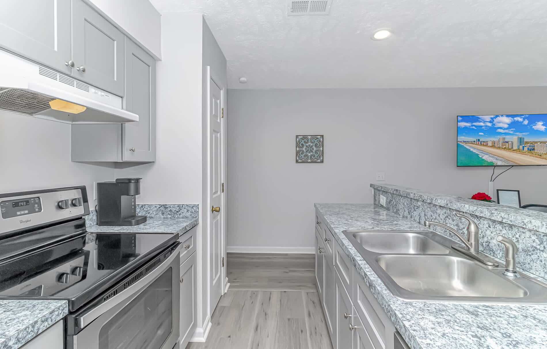 A compact kitchen with a built-in stove, a coffee maker, and a double sink.