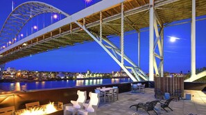 An outdoor seating area with a view of a bridge and a body of water at night. - Landing | Incredible 1BD, Clubhouse (Portland)