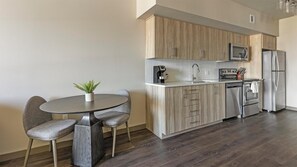A modern kitchen with wooden cabinets, stainless steel appliances, and a round dining table with chairs. - Landing | Incredible 1BD, Gym, Clubhouse (Portland)