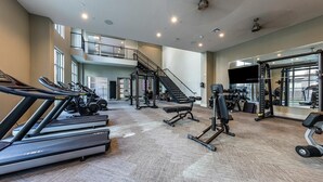 A spacious gym with treadmills, weight machines, and a staircase. - Landing | Spectacular 1BD, Pool, Gym (Austin)