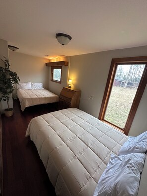 A bedroom with two beds, a nightstand, a lamp, a window, and a ceiling light. - The Yarborough Ranch is a spacious private retreat located in Lebanon, TN. (Lebanon)