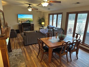 A living room with a fireplace, a television, a dining table with chairs, and a large window. - The Yarborough Ranch is a spacious private retreat located in Lebanon, TN. (Lebanon)