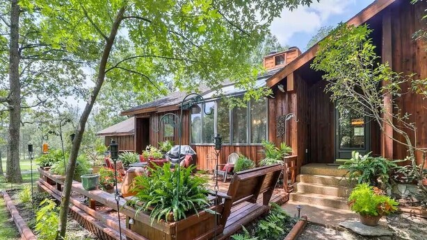 Une cabane en bois dotée d’un porche couvert, d’un espace salon extérieur et d’un jardin.