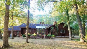 Un chalet rustique doté d’une véranda, entouré d’arbres.
