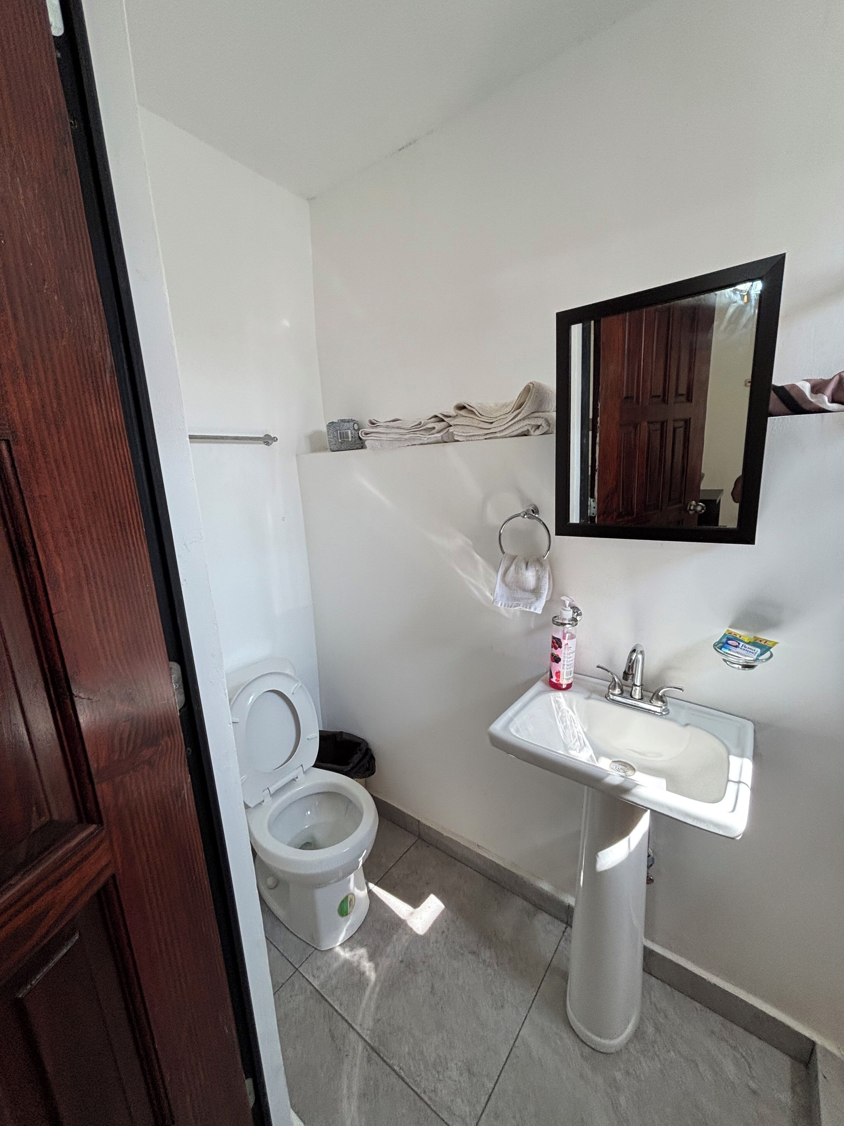 Ein Badezimmer mit Toilette, Waschbecken, Spiegel und Handtuchhalter.