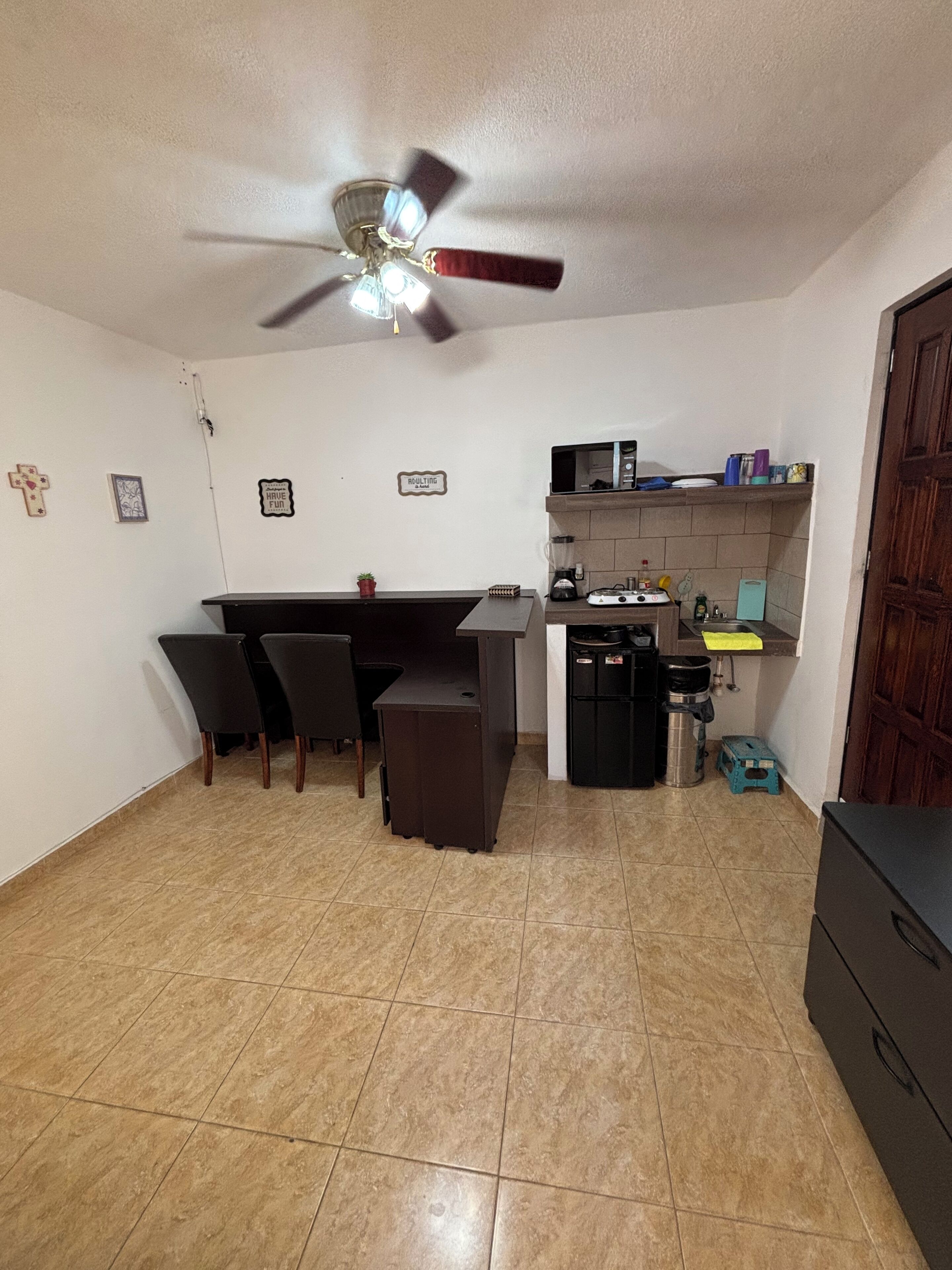 Eine kompakte Küche mit Essbereich, Deckenventilator und kleinem Kühlschrank.