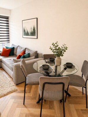 A modern living room with a glass dining table, grey sofa, and a potted plant. - Cosy Ladywell Retreat well connected to transport links and local shops (London)