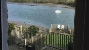 Vue sur une rivière depuis un balcon agrémenté de mobilier d’extérieur et d’une terrasse en bois.