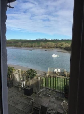 Blick auf einen Fluss von einem Balkon mit Gartenmöbeln und einer Holzterrasse.