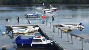 Un lac paisible où des bateaux sont amarrés à un quai, le tout entouré de verdure.